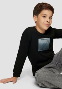 Zwarte lange mouwen T-shirt met een ronde halslijn, voorzien van een grijze grafische druk op de borst die een lijngrafiek toont tegen een gradient achtergrond.