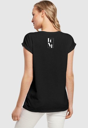 Sort kortærmet T-shirt med opkravede ærmer; har et hvidt grafisk design med teksten "KÆRLIGHED" på den øverste ryg; glat stof tekstur.