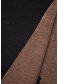 Tessuto in misto lana di colore nero e marrone, che mostra una texture liscia. I bordi sono finemente cuciti, evidenziando il contrasto di colore alla piega.
