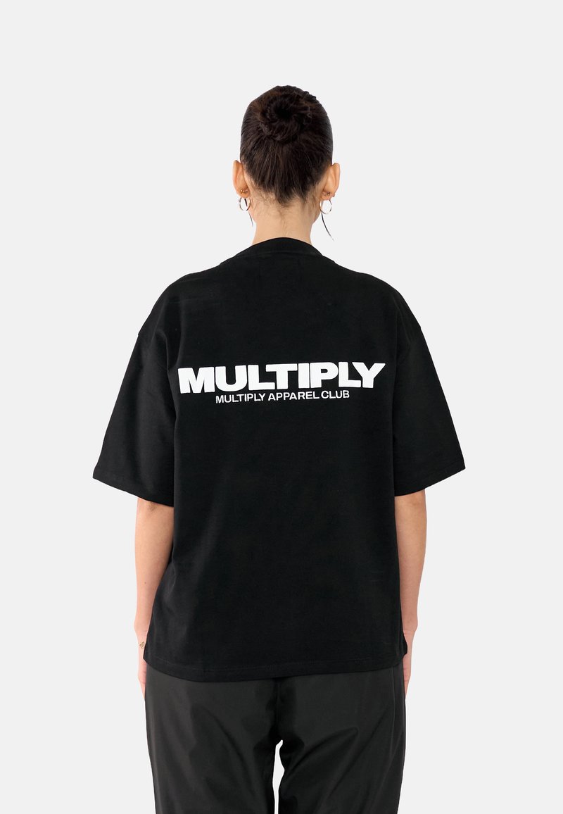 Černé oversized tričko s výrazným bílým textem "MULTIPLY" a "MULTIPLY APPAREL CLUB" na zadní straně. Krátké rukávy, volný střih, bavlněný materiál.