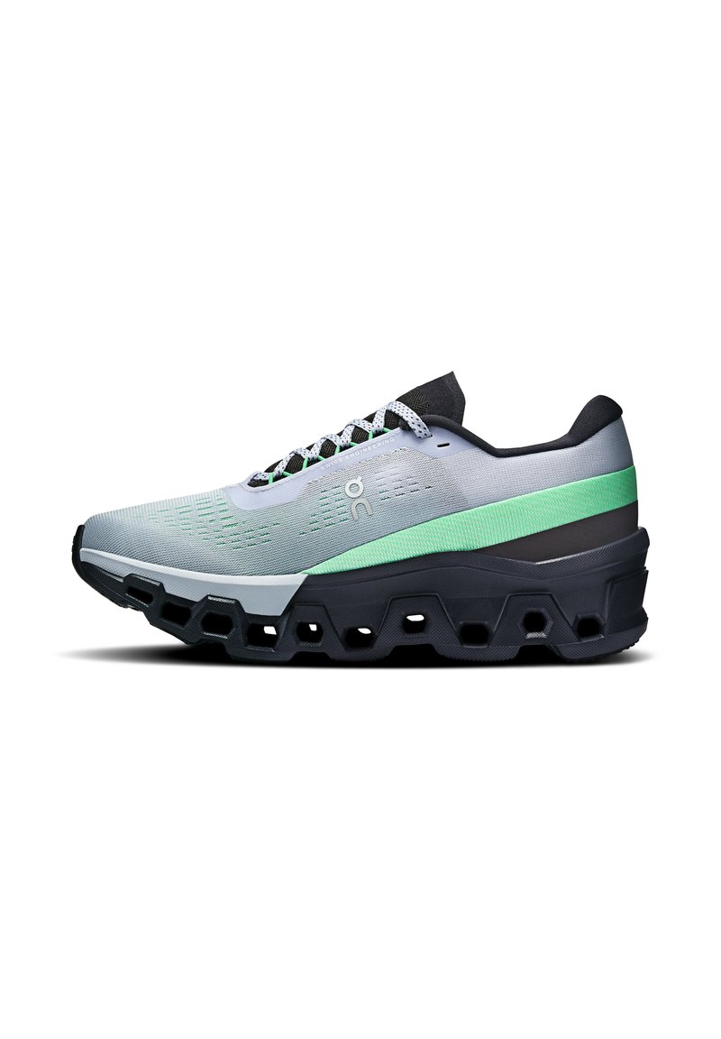 Chaussure de course gris clair avec un accent vert, dotée d'une tige en mesh texturé, d'une semelle noire épaisse avec des découpes hexagonales et de lacets plats.