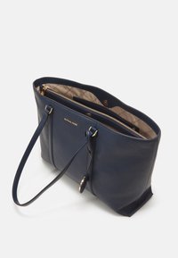 Sac fourre-tout en cuir bleu marine avec deux poignées, quincaillerie dorée et un intérieur beige clair présentant un motif matelassé.