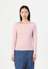 Lys rosa langermet topp med bred halslinje, mykt bomullsmateriale, kombinert med et jeansskjørt med synlige knapper og en frontsliss.
