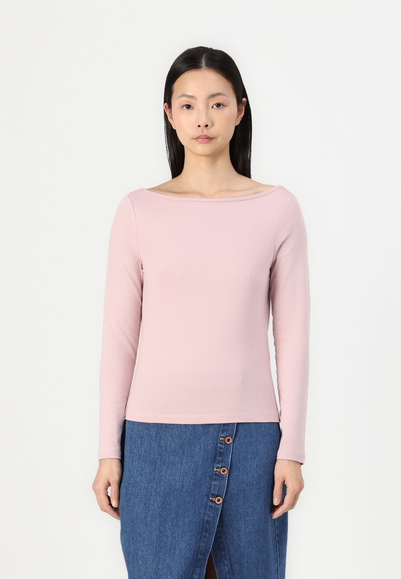 Lys rosa langermet topp med bred halslinje, mykt bomullsmateriale, kombinert med et jeansskjørt med synlige knapper og en frontsliss.