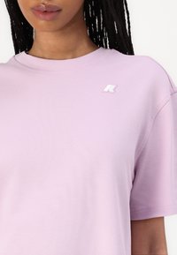 Light purple, short-sleeve T-shirt made of soft fabric with a round neckline and a small white logo on the chest. Smooth texture.