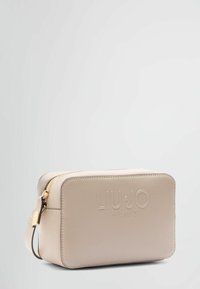 Beige rektangulært kosmetikksæt lavet af syntetisk materiale, med en guld lynlås og prægede logo på forsiden til branding.