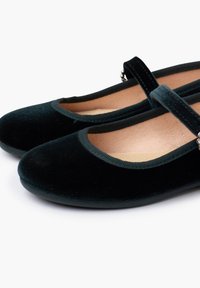 Ballerine in velluto verde scuro con punta arrotondata, bordo elastico morbido e una fascetta decorativa sul dorso del piede, con un accento in tono argento.