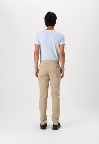 Lyseblå kortermet skjorte med v-hals, kombinert med beige chinos. Outfitten har enkle former og en uformell passform. Sorte sko fullfører stilen.