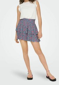 Mini gonna floreale con volants in blu, rosa e verde, abbinata a un top bianco senza maniche. Tessuto morbido con delicati bordi in pizzo.