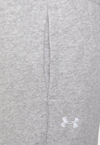 Grå sweatpants i mjukt tyg med en texturerad yta. Har en sidoficka och en vit logotyp på nedre benet.