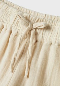 Tissu en lin beige avec une finition texturée, présentant une taille froncée et un nœud noué à l'avant.