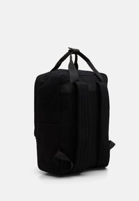Sac à dos en tissu noir avec bretelles rembourrées, poignée supérieure et poche latérale. Texture lisse avec un design minimaliste.