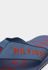 Μπλε σανδάλι slide με πορτοκαλί κέντημα «HILFIGER» στο υφασμάτινο λουρί και κόκκινο γραφικό σχέδιο στη σόλα.