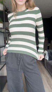 Sweater de malha canelada com riscas horizontais verdes e brancas, gola redonda, corte slim, combinado com calças de moletom cinzas largas.