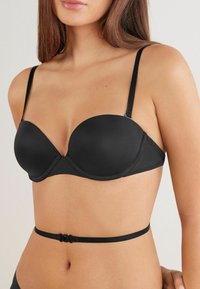 Sort underwired BH med glatte, formede skåle, tynde justerbare stropper og en diskret stropdetalje ved taljen, med en sikker lukning.