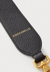 Cintura in pelle nera con superficie testurizzata, caratterizzata da un logo dorato "COCCINELLE" e un dettaglio della chiusura in metallo dorato.