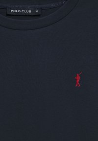 Mörkblå t-shirt i bomull med rund halsringning. Har en röd broderad logotyp av en figur som håller en golfklubba på bröstet.