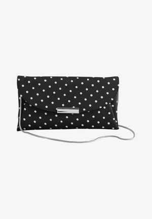 Pochette noire à pois blancs, fermoir argenté et fine bandoulière argentée sur fond blanc.