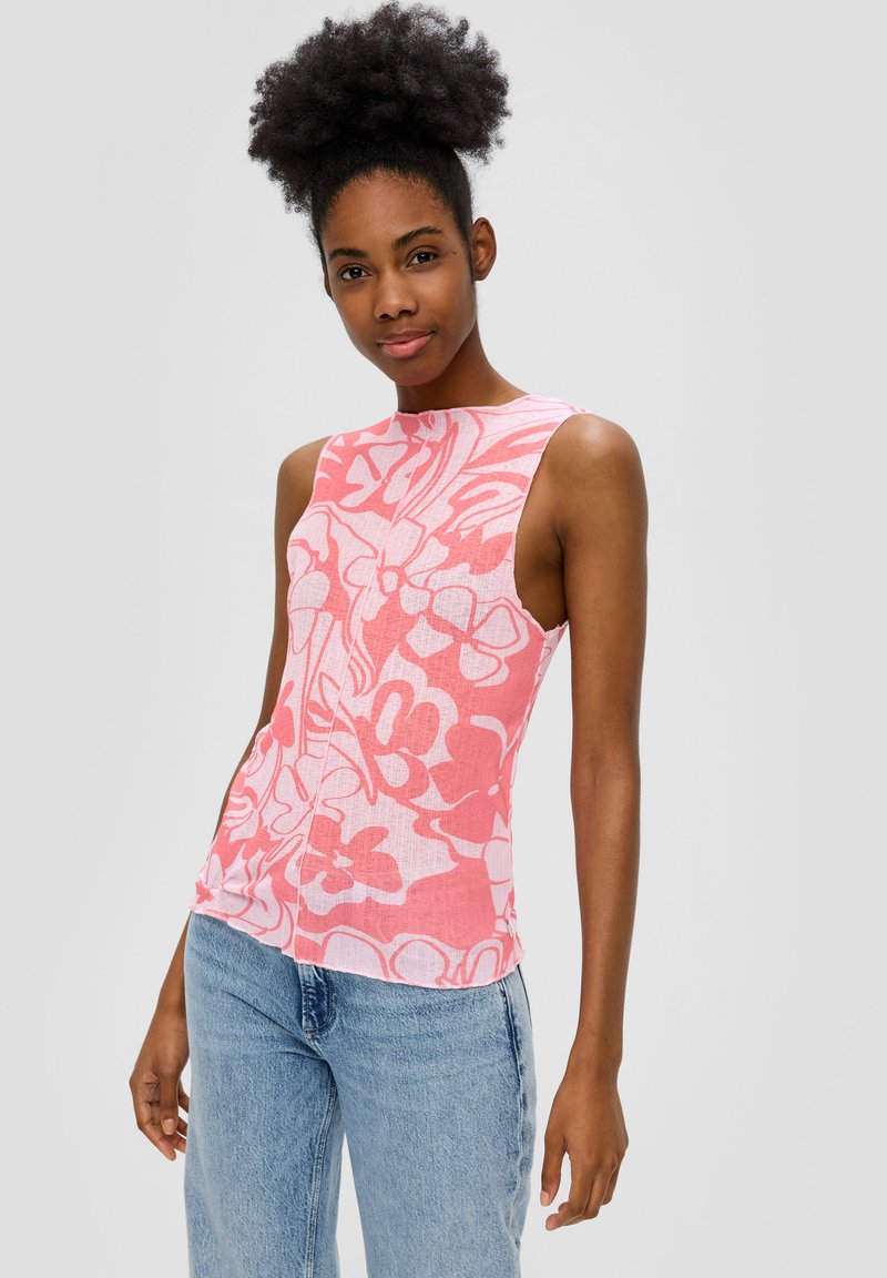Mouwloos topje in lichtroze met een wit bloemenpatroon, voorzien van een hoge halslijn en een rechte pasvorm, gecombineerd met lichtblauwe jeans.
