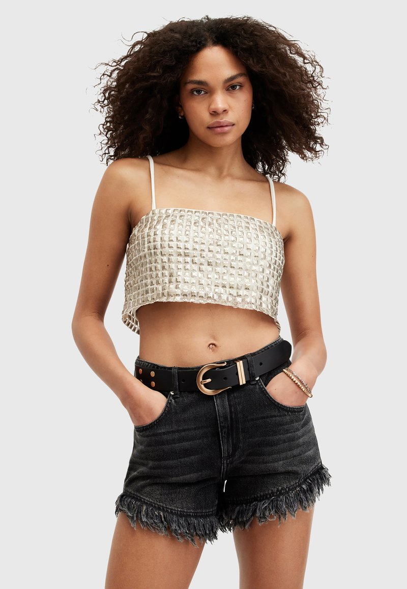 Top in tessuto metallico tagliato con motivo a quadrati, abbinato a pantaloni corti in denim neri a vita alta con orlo sfrangiato e cintura dorata.
