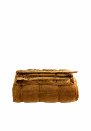 Couverture marron matelassée et veloutée pliée avec une texture douce et pelucheuse présentée sur un fond blanc.