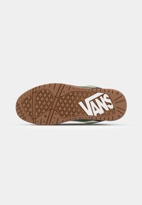 Vans sneakersål i brun gummi med et tekstureret mønster. Har et fremtrædende hvidt logo og et gitterlignende trækkraftdesign.