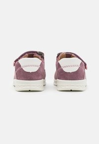 Sammet rosa sneakers med hvit gummi såle, som har en borrelåsrem og distinkte hvite detaljer på hælen. Flat, rund tådesign.