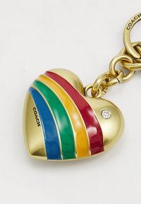 Gold heart-shaped keychain featuring colorful stripes in red, yellow, green, and blue, with a crystal accent and embossed 'COACH' logo.