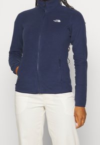 Marinefleecjacke mit hohem Kragen, durchgehendem Reißverschluss und zwei seitlichen Taschen. Mit Logo auf der linken Brust und strukturiertem Stoff.