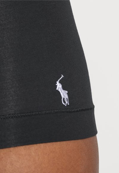 Črne oprijete kratke hlače iz gladkega materiala, z belim vezenim logotipom konja in jahača na levi strani.
