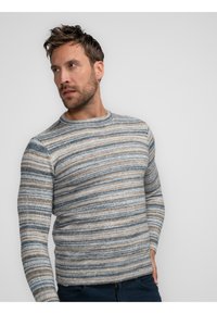 Pull rayé dans des tons de bleu, beige et marron. Encolure ronde, manches longues, ourlet côtelé et matériau en tricot doux et texturé.