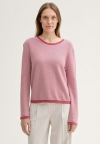 Texturierter Pullover in Rot und Pink, runder Ausschnitt, lange Ärmel, gerippter Saum und Bündchen, lässige Passform. Trägt man mit beigen Hosen.
