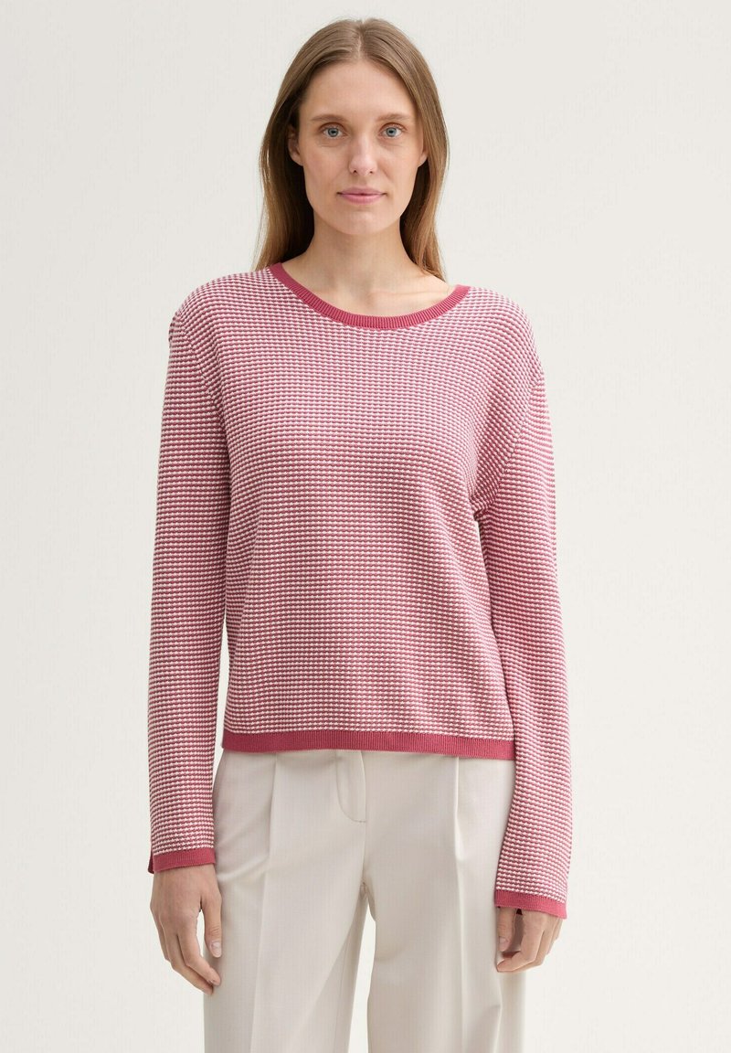 Texturierter Pullover in Rot und Pink, runder Ausschnitt, lange Ärmel, gerippter Saum und Bündchen, lässige Passform. Trägt man mit beigen Hosen.