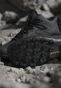 Zwarte wandelschoenen op rotsachtige ondergrond met gedetailleerde robuuste zool met Continental-logo voor betere grip en duurzaamheid.