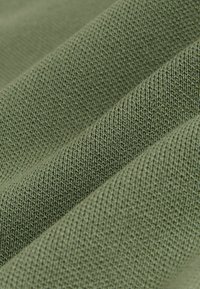 Primer plano de tela de punto verde oliva mostrando textura detallada y pliegues.
