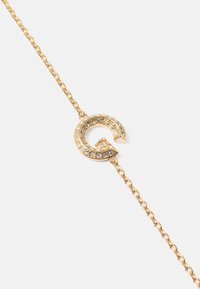 Gullkjedearmbånd med en sirkulær anheng med "G"-design, pyntet med klare rhinestones rundt kanten.