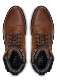 Hnědé kožené a semišové kotníkové boty s šněrováním, kontrastní námořnickou podšívkou a texturovaným vnitřkem. Viditelná značka "BULL BOXER".