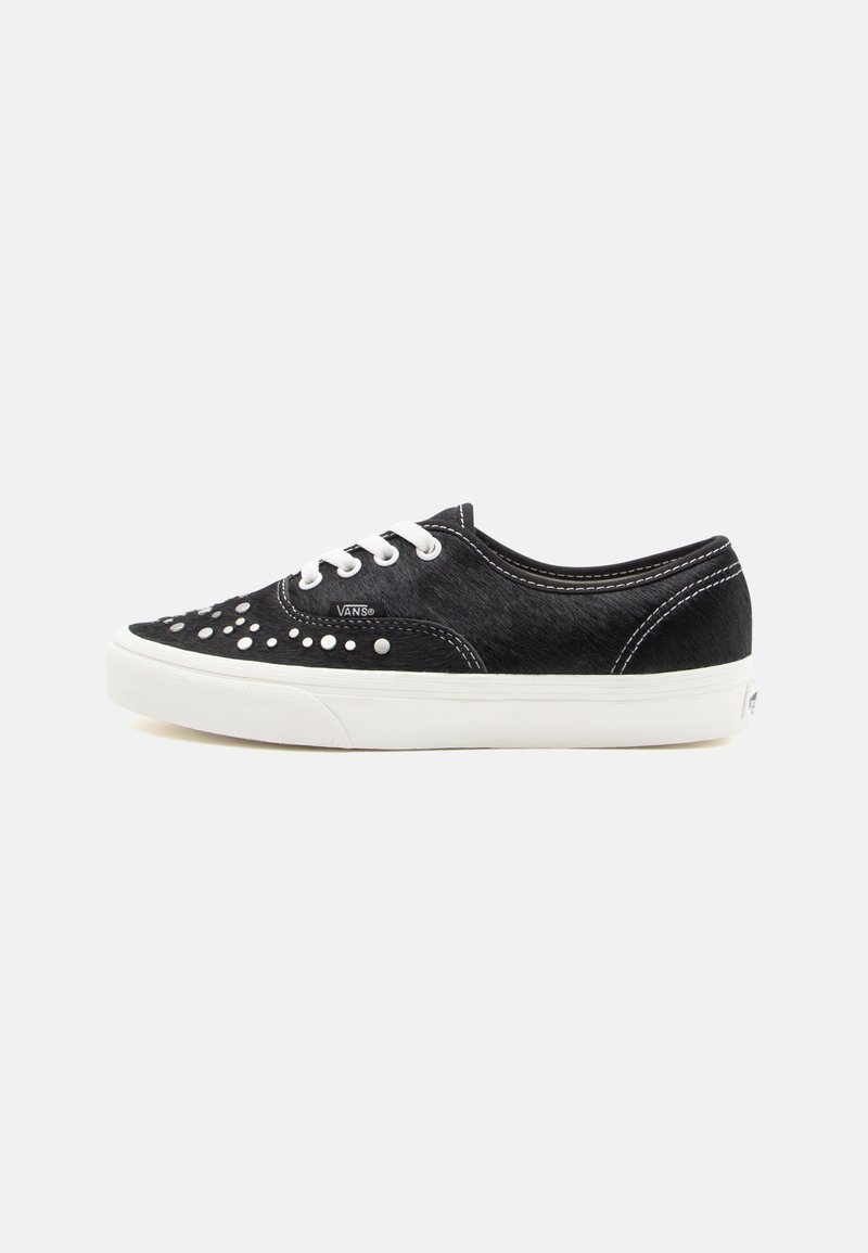 Zwarte vetersneakers met een gestructureerde bovenkant, voorzien van witte rubberen zolen en decoratieve studs op de teen. Kenmerkende Vans merkbranding.