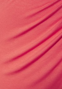 Koralo rožinės spalvos audinys su lygiu paviršiumi ir matomomis sukabintomis klostėmis, demonstruojantis lengvą, tramdomą medžiagą. Raštų ar akcentų nėra.