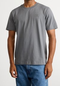 Gray cotton t-shirt with a crew neck and short sleeves; features a small, tonal adidas logo on the left chest; solid color, regular fit.