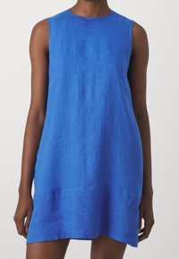 Robe trapèze en lin bleu avec un col rond et un design sans manches. Le tissu a une texture douce et présente un ourlet droit.