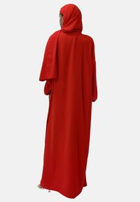 Abaya rouge ample avec des manches larges et une capuche assortie. Tissu lisse avec une silhouette fluide. Pas de motifs ni de ferrures visibles.
