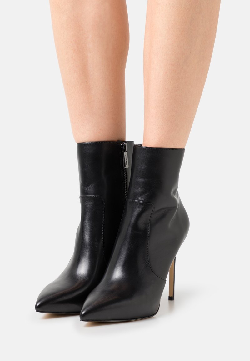 Stivaletti neri in pelle con punta affusolata e zip laterale, caratterizzati da un design elegante e tacco a stiletto alto. Texture liscia e lucida.