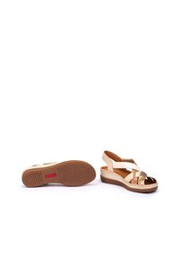 Sandalias de cuña beige y doradas con suela texturizada, punta abierta y diseño de tiras entrelazadas. Presenta una parte superior sintética y plantilla acolchada.