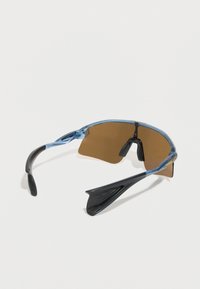 Αθλητικά γυαλιά ηλίου με μπλε πλαίσιο, καφέ καμπυλωτούς φακούς και μαύρα ρυθμιζόμενα μαξιλαράκια μύτης σε λευκό φόντο.
