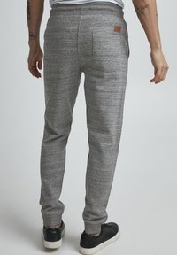 Gray athletic joggers with a textured finish, elastic waistband, two back pockets, and a subtle brand patch near the waistband.