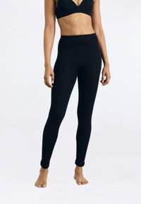 Fekete, magas derekú leggings sima, rugalmas anyagból, testhezálló kialakítással, tiszta, befejezett szegéllyel a bokánál.