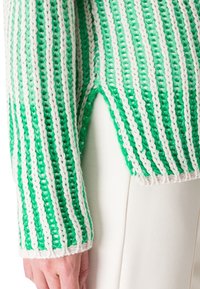 Grün-weiß gestreifter Strickpullover mit grober Textur, seitlichem Schlitz und gerippten Bündchen.
