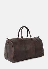 Braune Leder-Reisetasche mit goldfarbenen Beschlägen, abgerundeter Form, zwei stabilen Griffen und einer polierten Textur. Verfügt über einen Reißverschlussverschluss und seitliche Schlaufen.