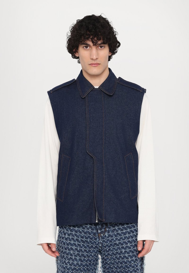 Denim vest with a collar, front zipper, and angled seams. Dark blue color with contrasting stitching; features two front pockets.